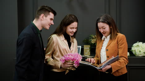 asian woman showing a sample book to a couple