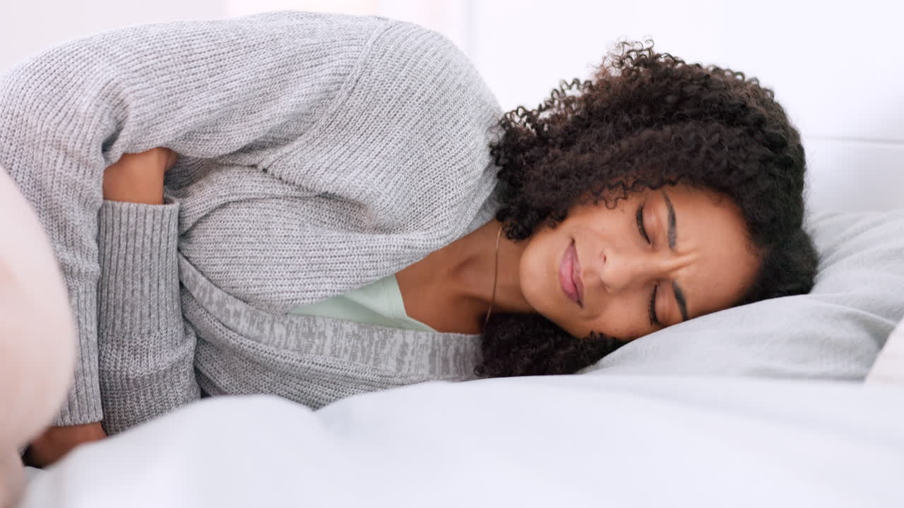 cama, dolor de estómago y una mujer joven haciendo masaje