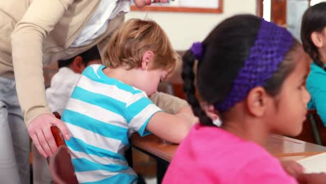 pretty teacher helping schoolboy at his desk