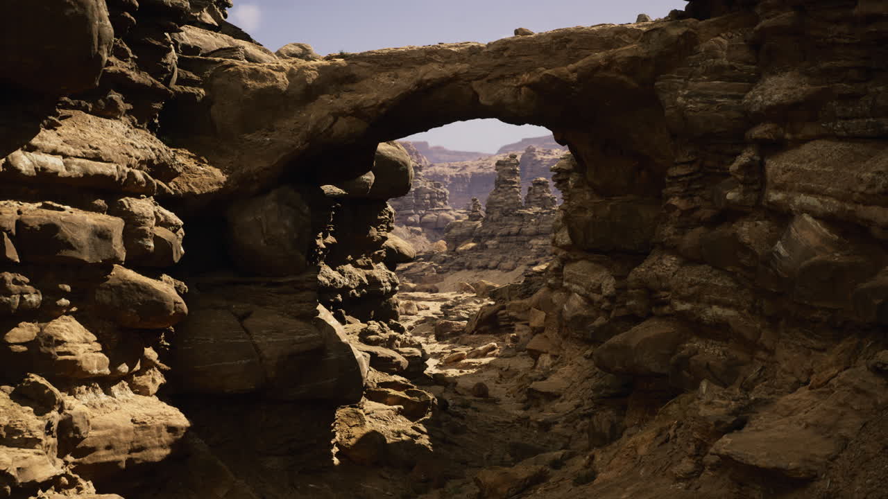 Vast rocky landscape featuring a natural stone arch against clear skies