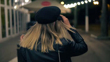 Ein-Schönes-Mädchen-Mit-Stylischem-Hut-Und-Schwarzer-Lederjacke-Geht-Im-Licht-Einer-Café-Lampe-Durch-Den-Nachtpark-1