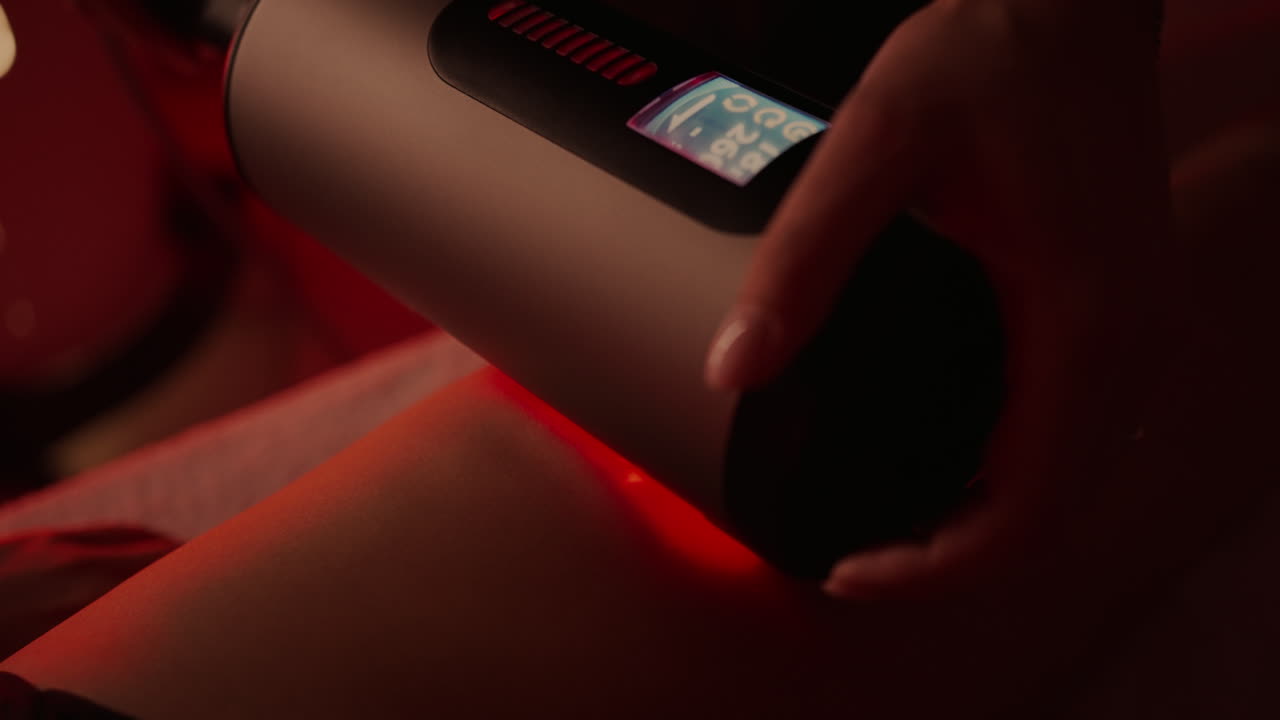 Woman using a red light therapy device on her leg