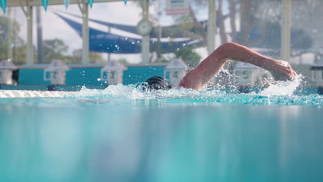 Cámara-Lenta-De-Cerca-En-La-Superficie-Del-Agua-De-Un-Nadador-Profesional-De-Estilo-Libre-Con-Gorra-Haciendo-Vueltas-En-La-Piscina-Al-Aire-Libre