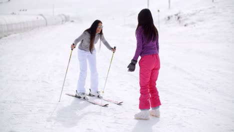 young woman teaching her friend to ski