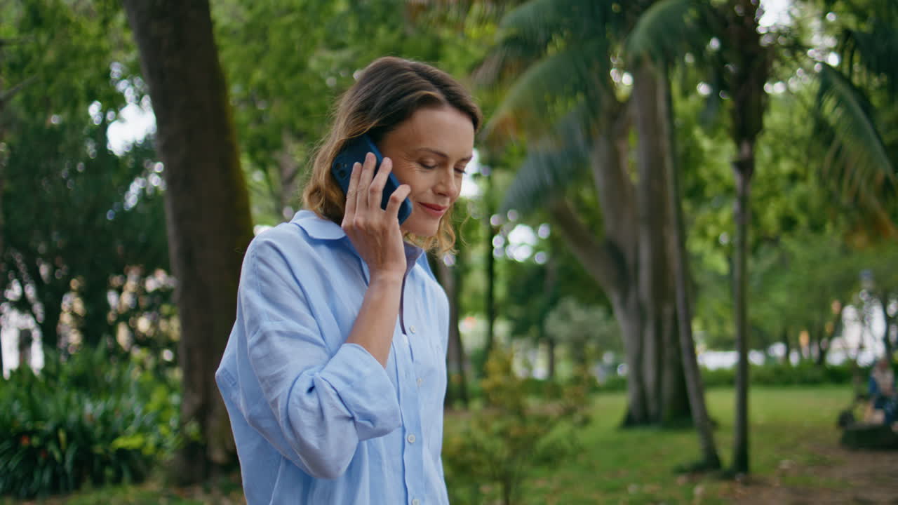 Relaxed woman strolling park calling mobile phone closeup. Smiling lady talking