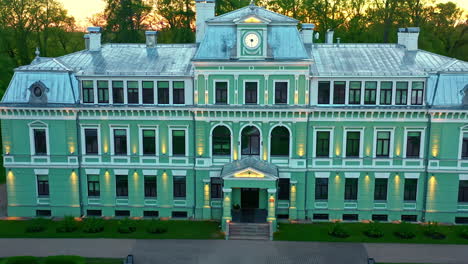 front view of kokmuiža manor in latvia with lights on during evening sunset