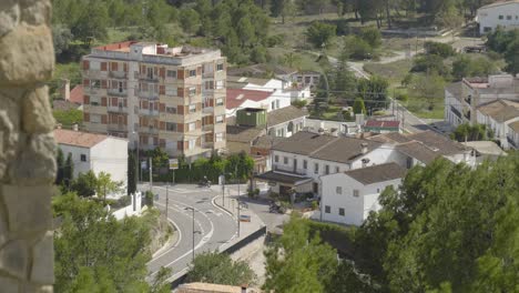 cars drive around a tight corner in the small spanish village of chulilla