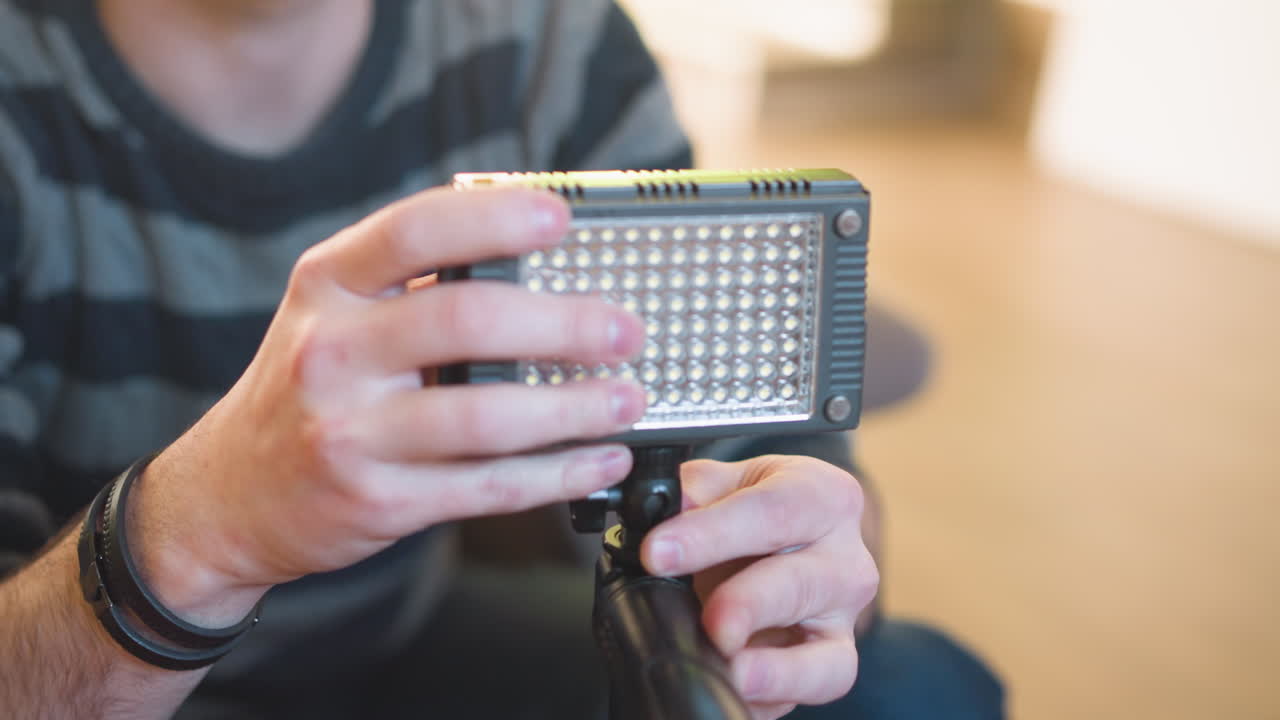Studio guy handling microphone setup, adjusting it for filming. Close-up of hands on microphone, studio gear in focus with blurred background. Preparation for video or sound recording session