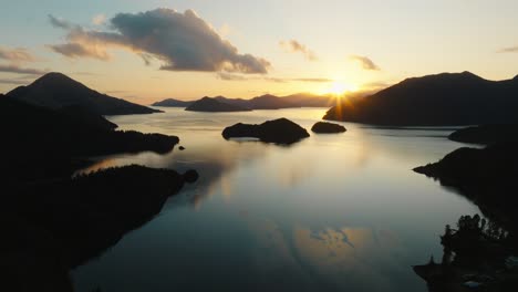 aerial view of golden sunrise and silhouetted peninsula landscape with calm reflective waters in the pelorus sound te hoiere of marlborough sounds, south island of new zealand aotearoa