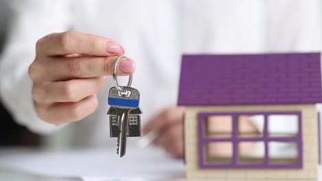 insurance agent or real estate agent holds house key closeup