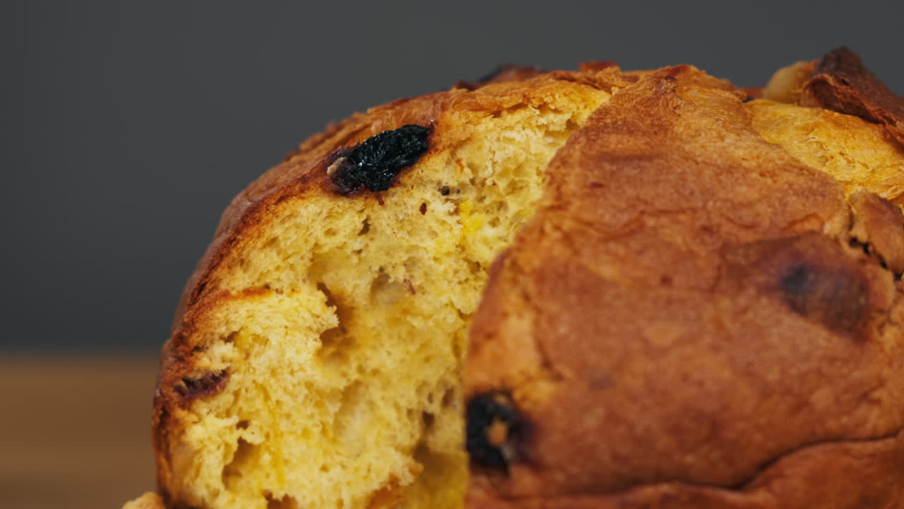 Traditional English Christmas cake tied with a jute thread on the black background. Italian classic Panettone .Pastry Chef sprinkles powdered sugar through a sieve on the fruit Easter cake with raisins. High quality 4k footage