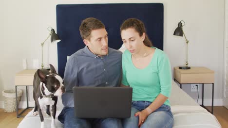 A-young-caucasian-couple-talking-and-paying-their-bills-using-a-laptop