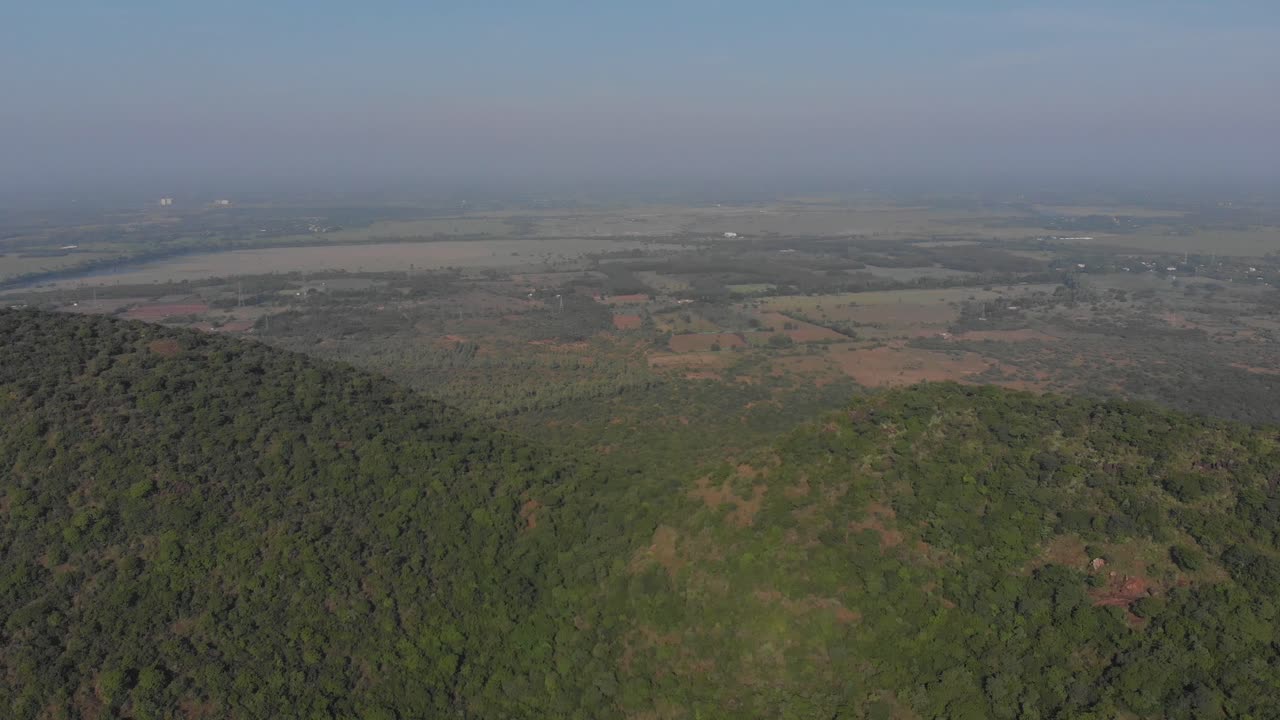 flotando sobre una montaña boscosa en india antes de volar frente a las dos cimas de las colinas contiguas