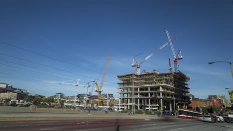 lapso de tiempo de construcción y movimiento de grúas con tráfico de vehículos en primer plano