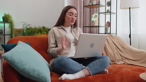 Woman-sitting-on-home-couch,-looking-at-camera,-making-video-conference-call-with-friends-or-family