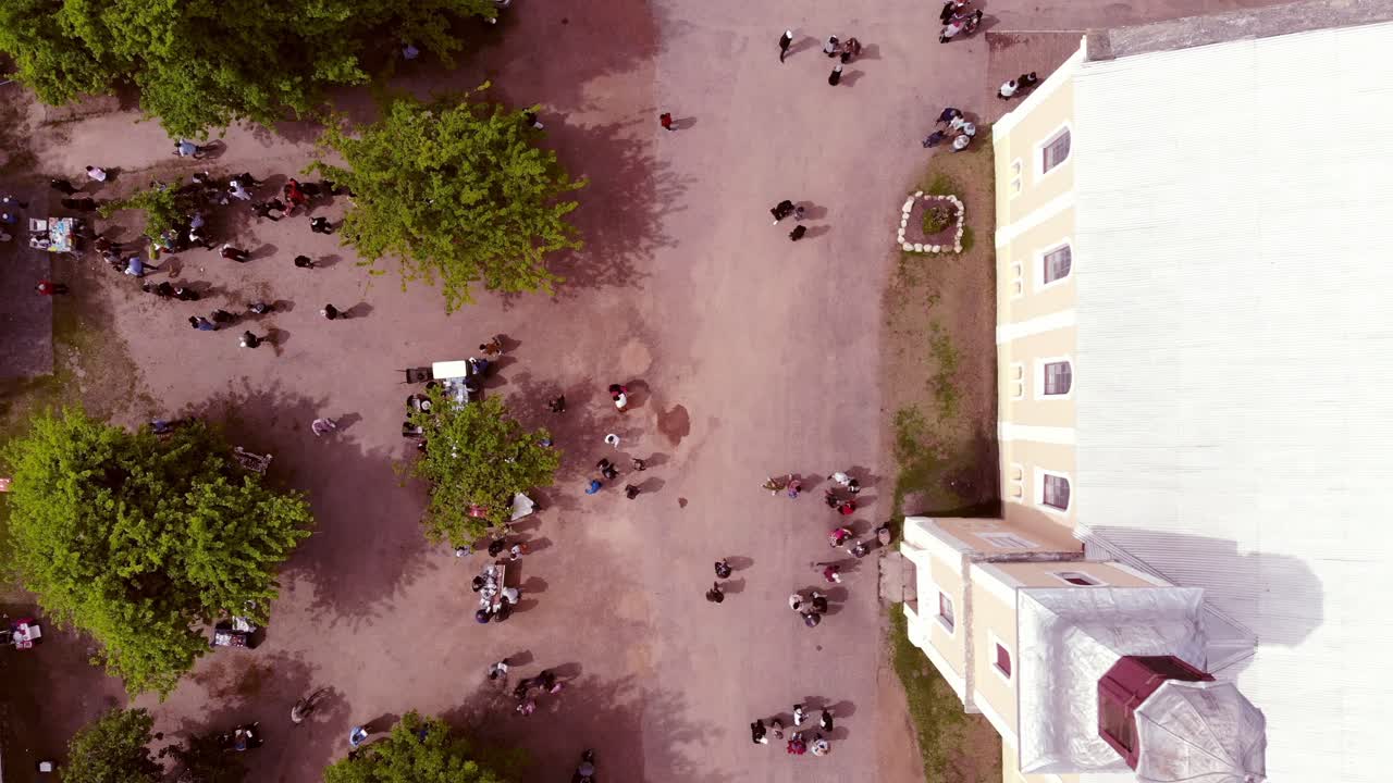 Wide drone shot flies over the street market, whilst it reveals the crowd of people coming out from the Moravian church.