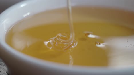 close up of honey being poured into a white bowl