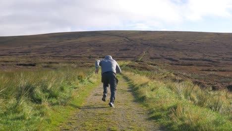 Männlicher-Sprinter-Läuft-Schnell-Auf-Dem-Pfad-In-Den-Wicklow-Mountains,-Irland-An-Einem-Frühen-Sonnigen-Morgen---Totale-Aufnahme