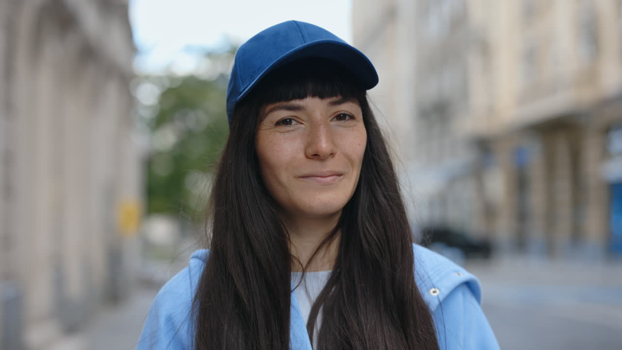 Portrait of a brunette woman with freckles wearing a blue cap in the city