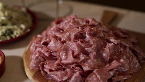 Thinly-sliced-salami-on-a-wooden-board,-medium-close-up