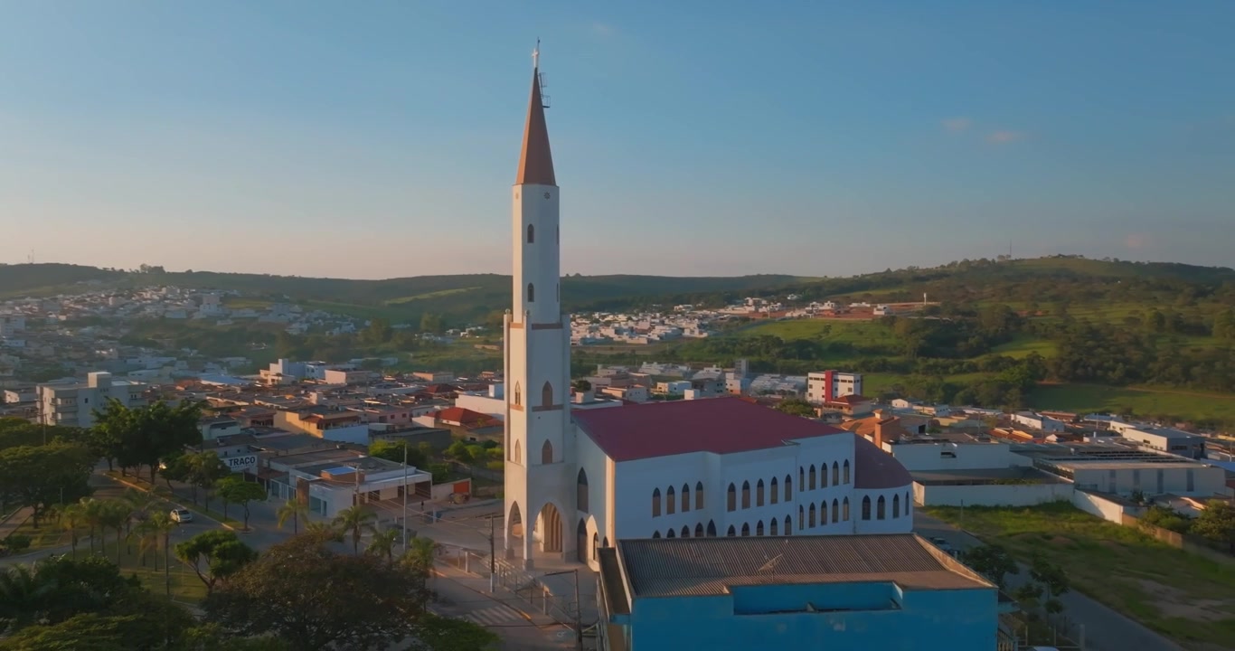Chiesa di Sant'Antonio che si erge sopra il centro di Santo Antônio do Monte, Minas Gerais, Brasile, architettura religiosa e paesaggio urbano circondato da dolci colline, ripresa aerea con drone in discesa orbitale per inquadratura di apertura.
