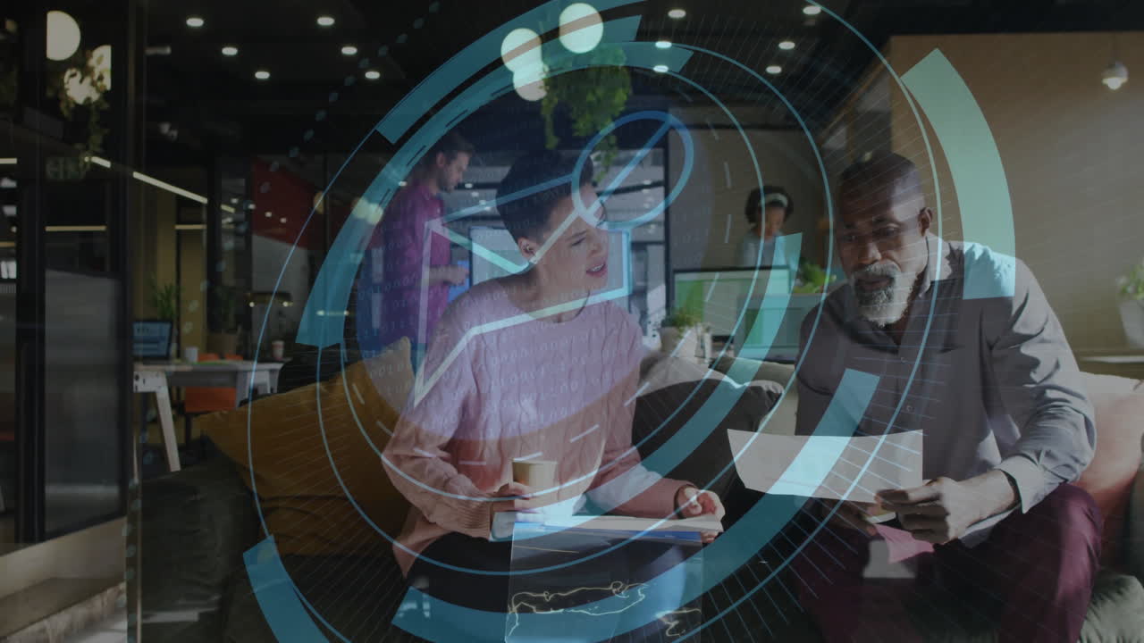 Coworkers collaborating over documents in office lounge, showcasing technology dashboards and code