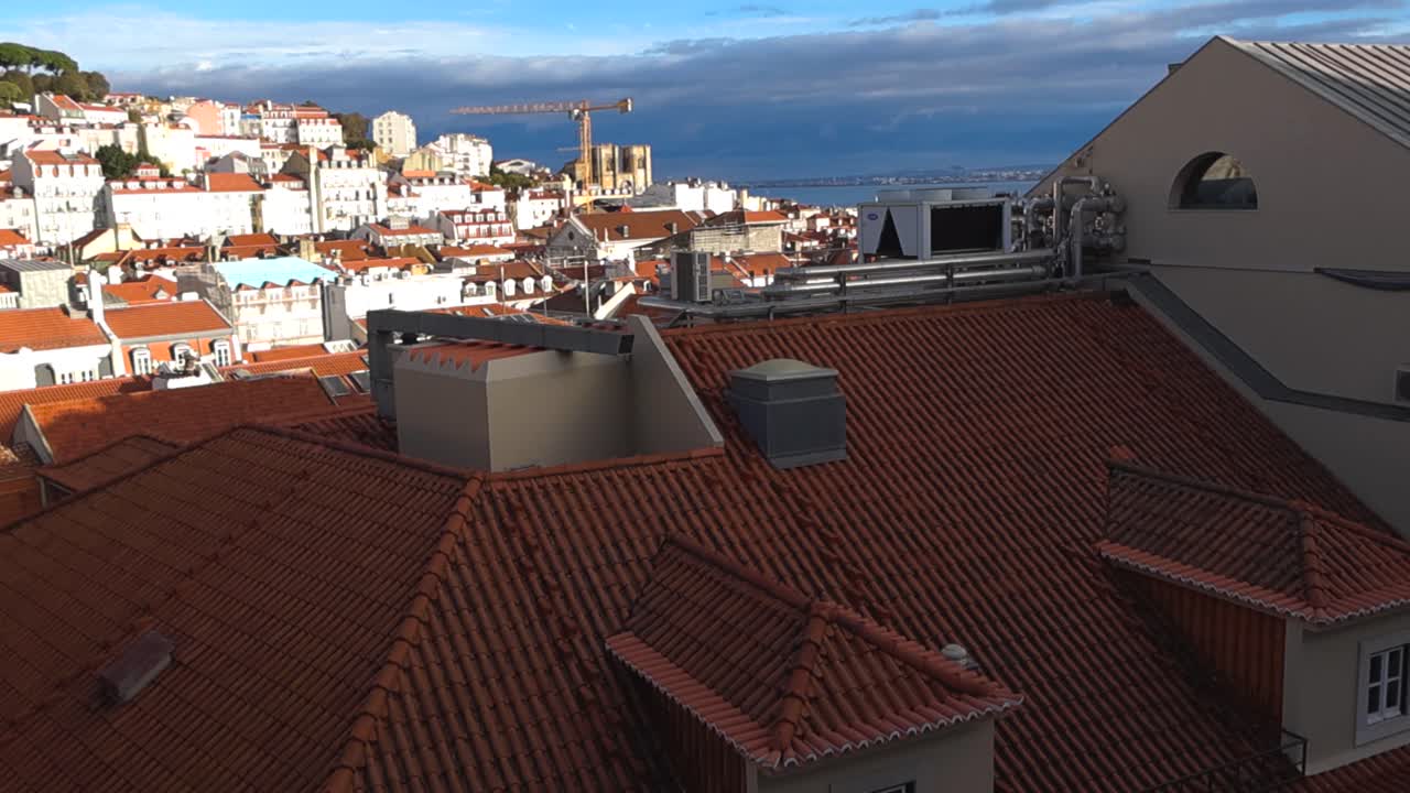 Slow pan across traditional red rooftops and white historic buildings with a distant river backdrop, captured from a famous scenic viewpoint on a sunny day