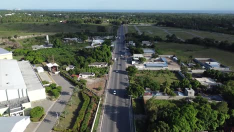 aerial view of drone focusing from bottom to top long road of bani in dominican republic, beautiful mountains in background, concept travels out of town