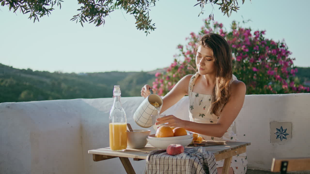 유리 전망 테라스에서 물을 부는 만적인 여인. 아침 식사를 하는 여자