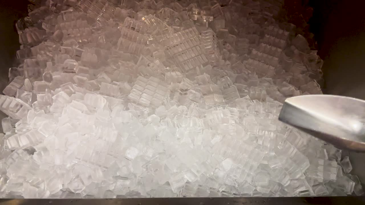 A person scoops ice into a cup at a Korean BBQ in Bangkok. The scene is well-lit, focusing on the ice and hands