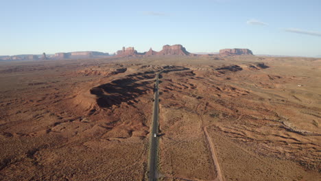 High-Drone-footage-of-RV,-motorhome-driving-along-iconic-forest-Gump-highway-in-Monument-Valley,-Utah-on-American-road-trip