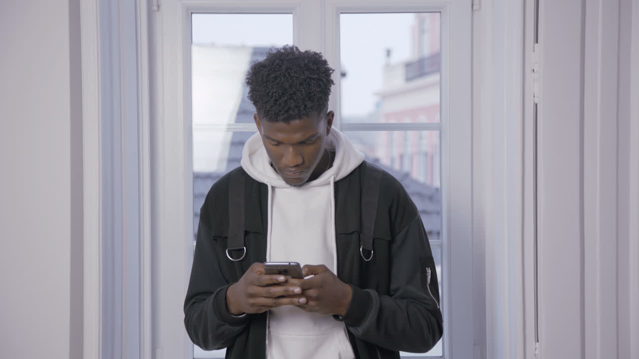 Serious African American student texting message on smartphone