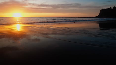 Impresionante-Puesta-De-Sol-Pinta-El-Cielo-Sobre-Una-Playa-Serena-Con-Majestuosos-Acantilados.