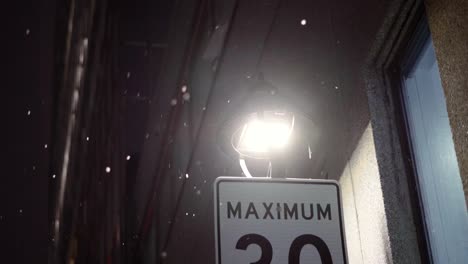 slow motion shot of light snowfall falling above a speed sign in montreal canada