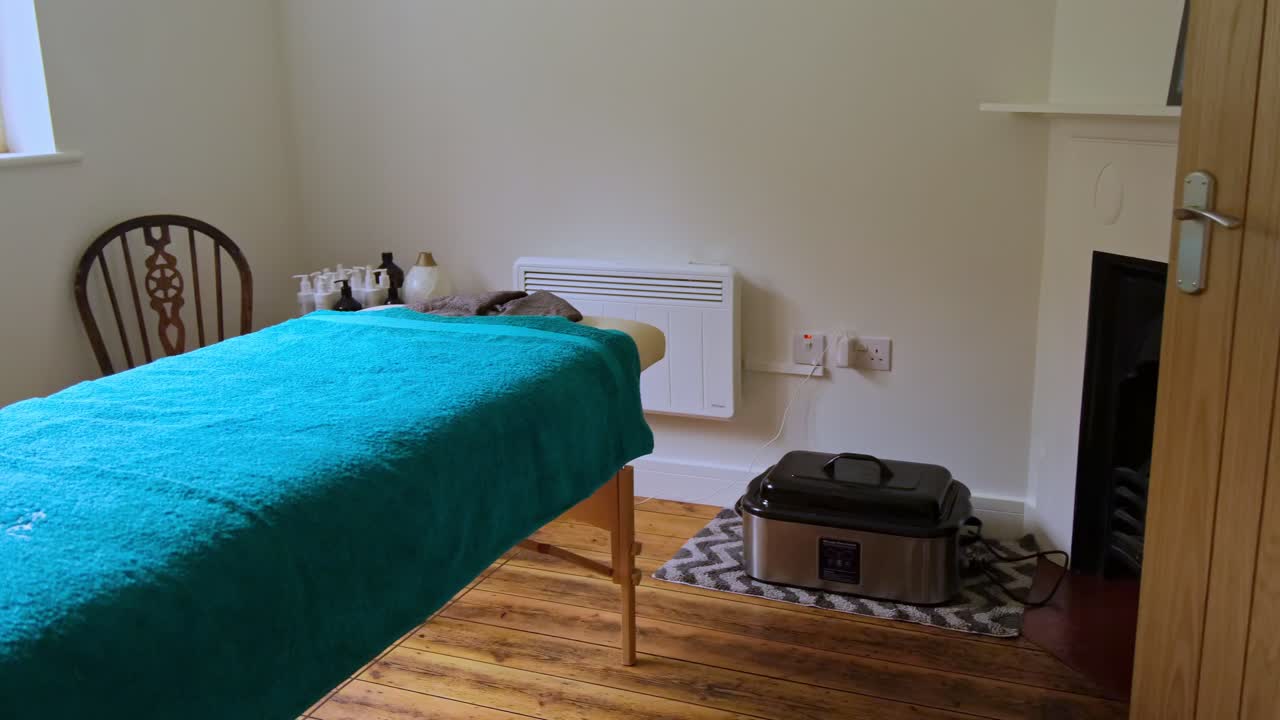Pan shot of empty relaxing room of massage table, towels, warm rocks, oils.