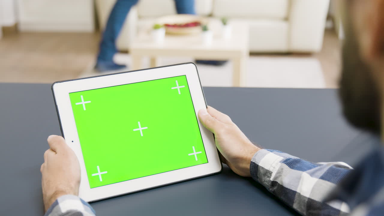 녹색 화면을 가진 태블릿을 사용하는 사람
