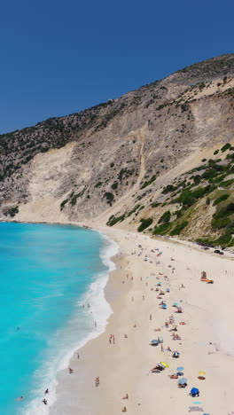 tourist relaxing under colorful umbrellas at sunny mediterranean beach of myrtos, greece, kefalonia