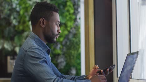 hombre de negocios afroamericano usando una computadora portátil en una cafetería