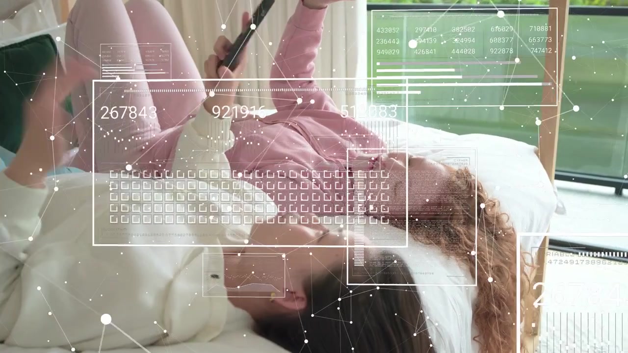 Two women on bed tapping phones, starting holographic UI updates and comparing screens for tech