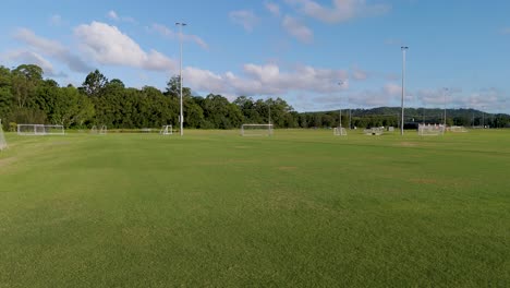 aerial footage of an empty soccer field with clear skies and lush greenery, captured by a drone
