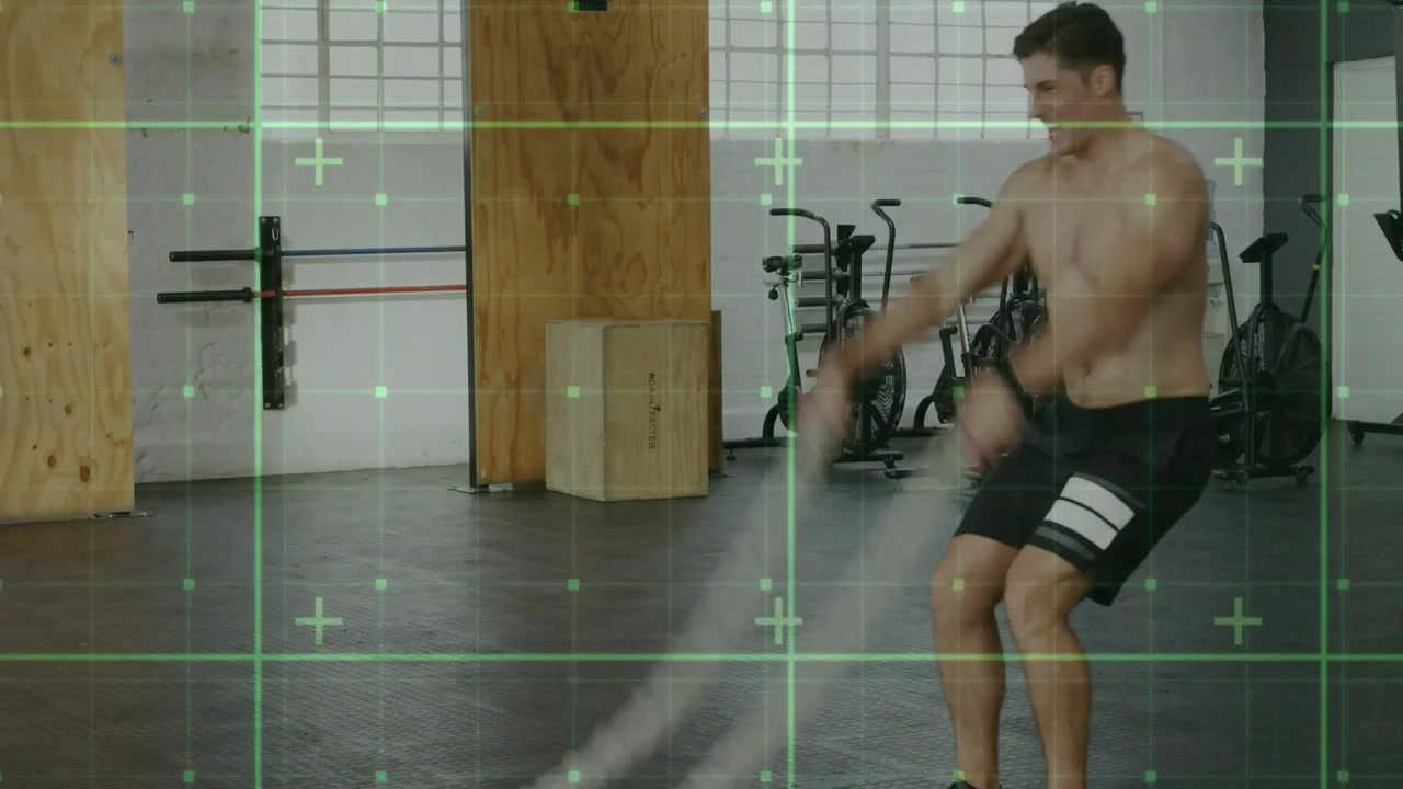 Atleta maschio che esegue onde alternate con le battle ropes in palestra, con una griglia verde che traccia la forma per la potenza.