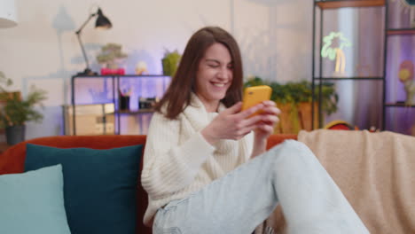 mujer joven feliz en casa usar teléfono inteligente escribir navegación wow sí descubrió gran gran victoria celebrar