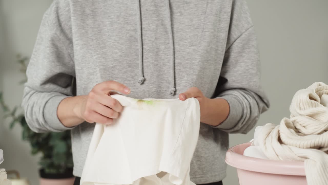 Hands Rubbing a Green Stain on a White Garment