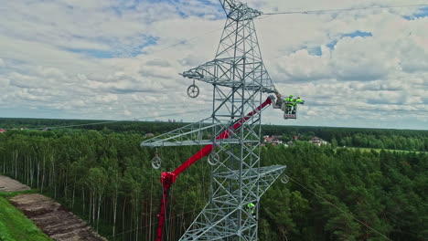 aerial shot of technicians on lifting crane working on high voltage electricity tower in their uniform