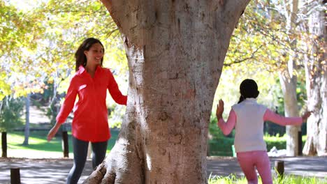 mother and daughter playing in park under tree