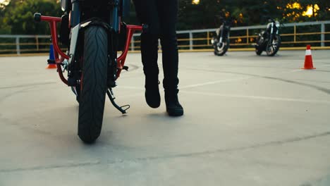 Close-up-shot-of-a-girl-driving-a-motorcycle-at-a-training-ground-in-a-motorcycle-school.-Lots-of-motorcycles-in-the-background