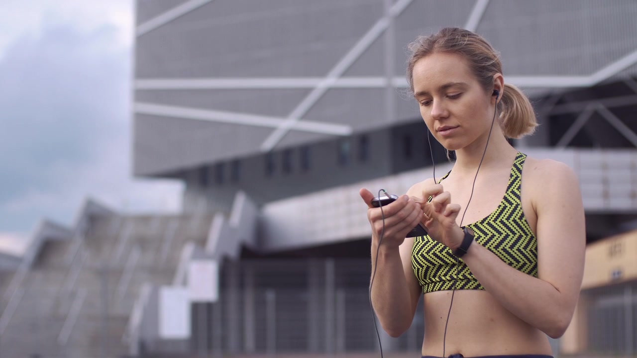 Female Athlete Using Smartphone and Earphones in Urban Environment