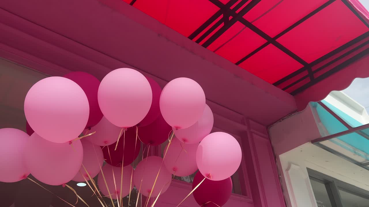 los globos rosados festivos giran en la apertura de una nueva tienda en un centro comercial al aire libre