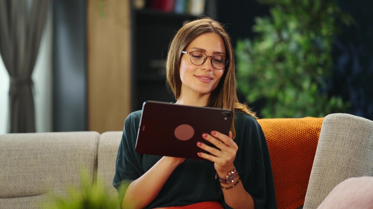 Young Woman Using a Tablet on a Sofa at Home
