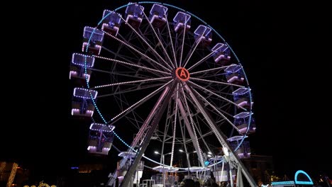 colorful ferries wheel with neon lights rotating on city square on holidays